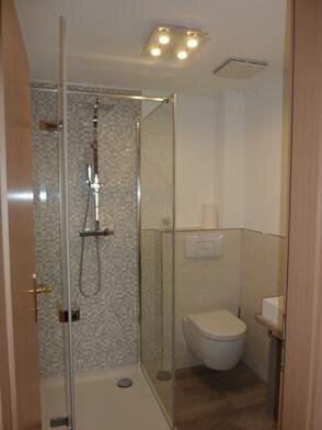 Bild 4 moderne ebenerdige Dusche mit höhenverstellbaren Duschkopf und Glaswänden

spülrandloses WC,

Wasserbecher und Fön vorhanden. Hand- und Duschtücher inklusive (Wechsel 2x wöchentlich)